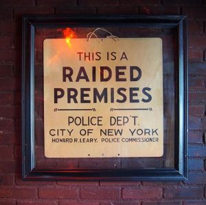 A "Raided Premises" sign from the Stonewall Uprising, now located inside the Stonewall Inn, 2016. Image courtesy of Rhododentrites, Wikimedia Commons.