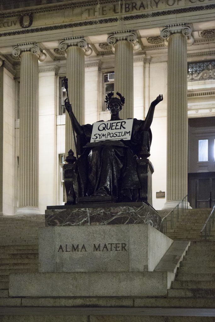 Picture of a statue outside of Earl Hall at Columbia University. A sign reading "Queer Symposium" has been placed in the statue's lap.